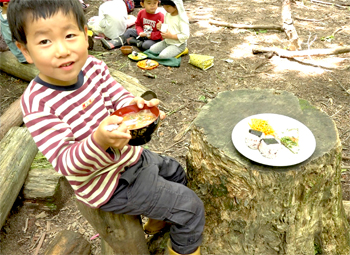 山で給食をいただく子どもたち