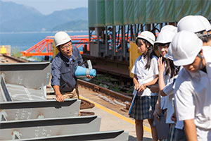 造船所で佐々木氏の話を聞く生徒たち