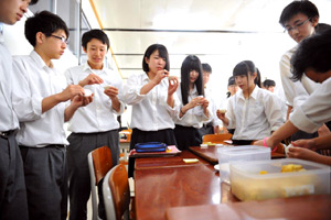 自分たちのアイデアがもとになってできた試作品を口に運ぶ高校生たち